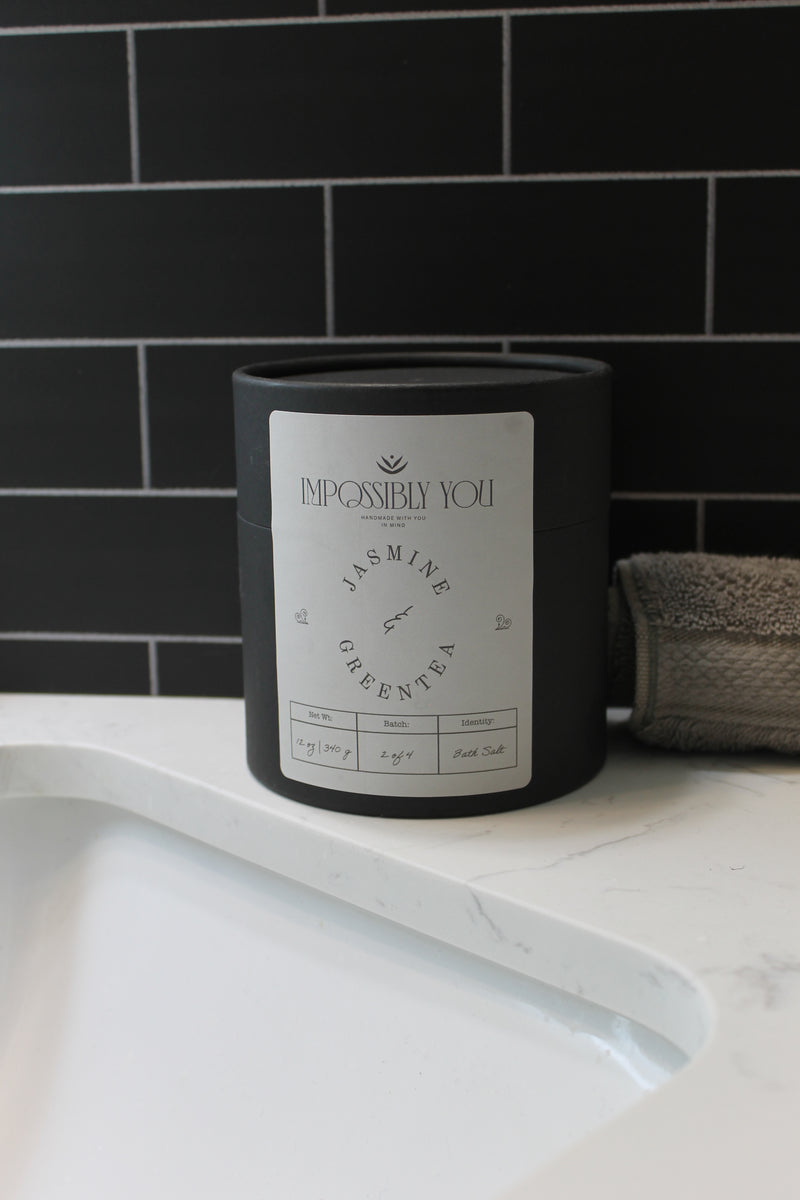 Impossibly you jasmine and green tea bath salts next to a bath room sink and a towel