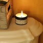 Lit scented soy wax candle in a bathroom.