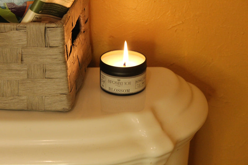 Lit scented soy wax candle in a bathroom.
